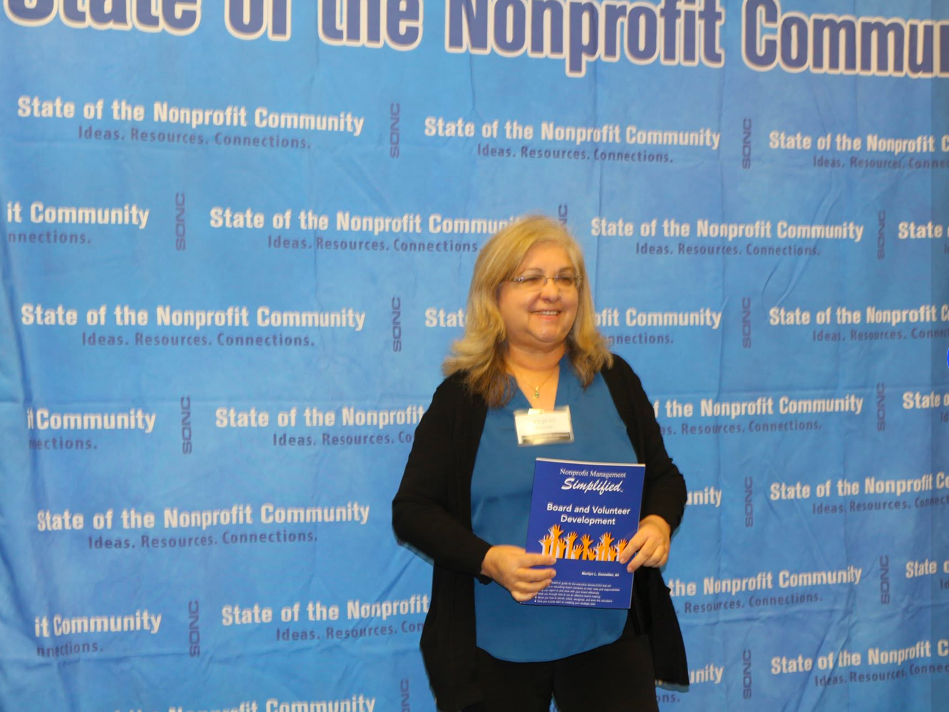 Attendee posing with a book in front of the SONC step-and-repeat banner